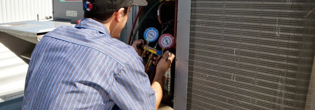 HVAC technician servicing a condenser unit in Brenham