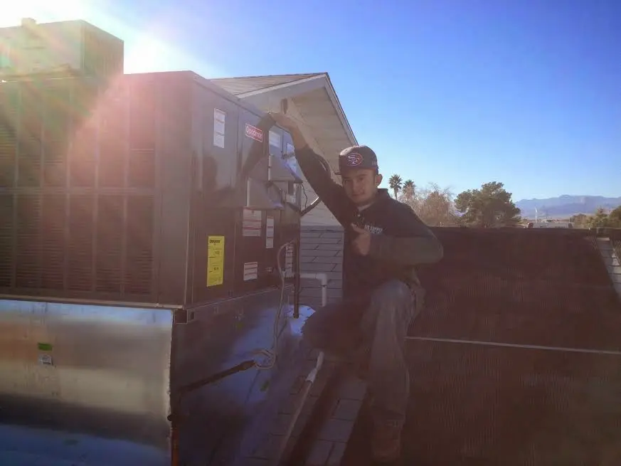 HVAC technician performing Heat Pump Repair on a rooftop unit in Brenham